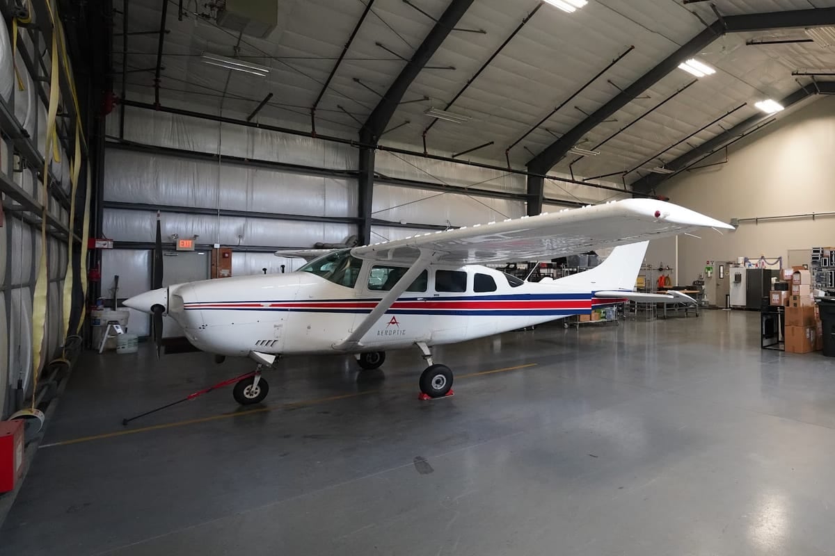 Aeroptic Cessna TU206 mapping aircraft parked in a white and gray high-bay hangar