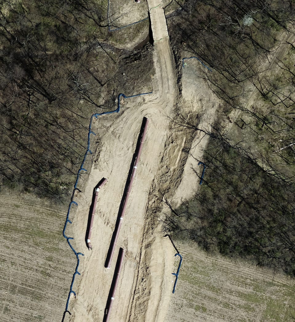Aerial view of pipe sections laid along a cleared pipeline right-of-way